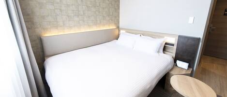 Une chambre d’hôtel avec un grand lit, une table de chevet et une tête de lit dotée d’un panneau lumineux.