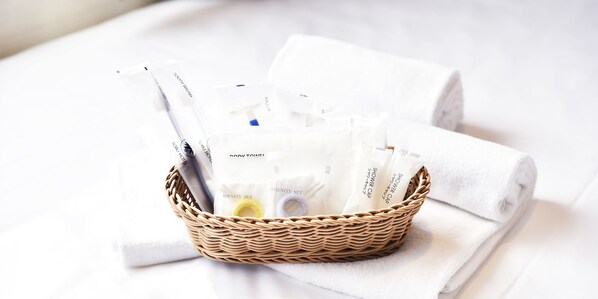 A wicker basket containing toiletries and towels on a white bed. - Kawagoe Tobu Hotel (Kawagoe)