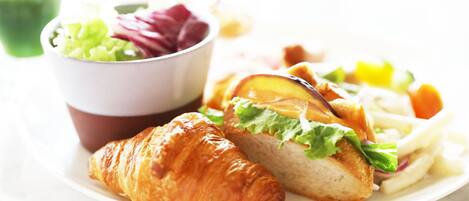 A plate with a sandwich, a croissant, and a salad.