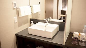 Un baño de hotel con un lavamanos blanco, un espejo y un perchero para toallas.