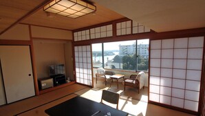 A traditional Japanese-style room with tatami flooring, a low table with a tray of tea utensils, and a television. - Kashikojima Hotel Bay Garden (Shima)