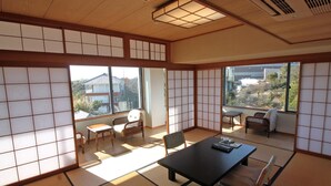 A traditional Japanese room with tatami flooring, sliding shoji doors, and a view of a residential area. - Kashikojima Hotel Bay Garden (Shima)