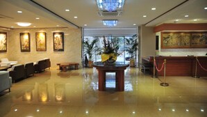 A hotel lobby with a reception desk, seating area, and artwork on the walls. - Kashikojima Hotel Bay Garden (Shima)