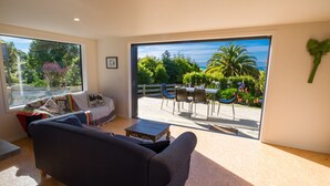 A living room with a sofa, a coffee table, and a view of an outdoor patio with a table and chairs.