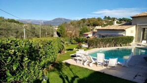 A pool area with lounge chairs, a well-maintained lawn, and a view of mountains in the background. - Villa with terraces and swimming pool panoramic view. Near golf courses and beach, 1km from village (Valbonne)