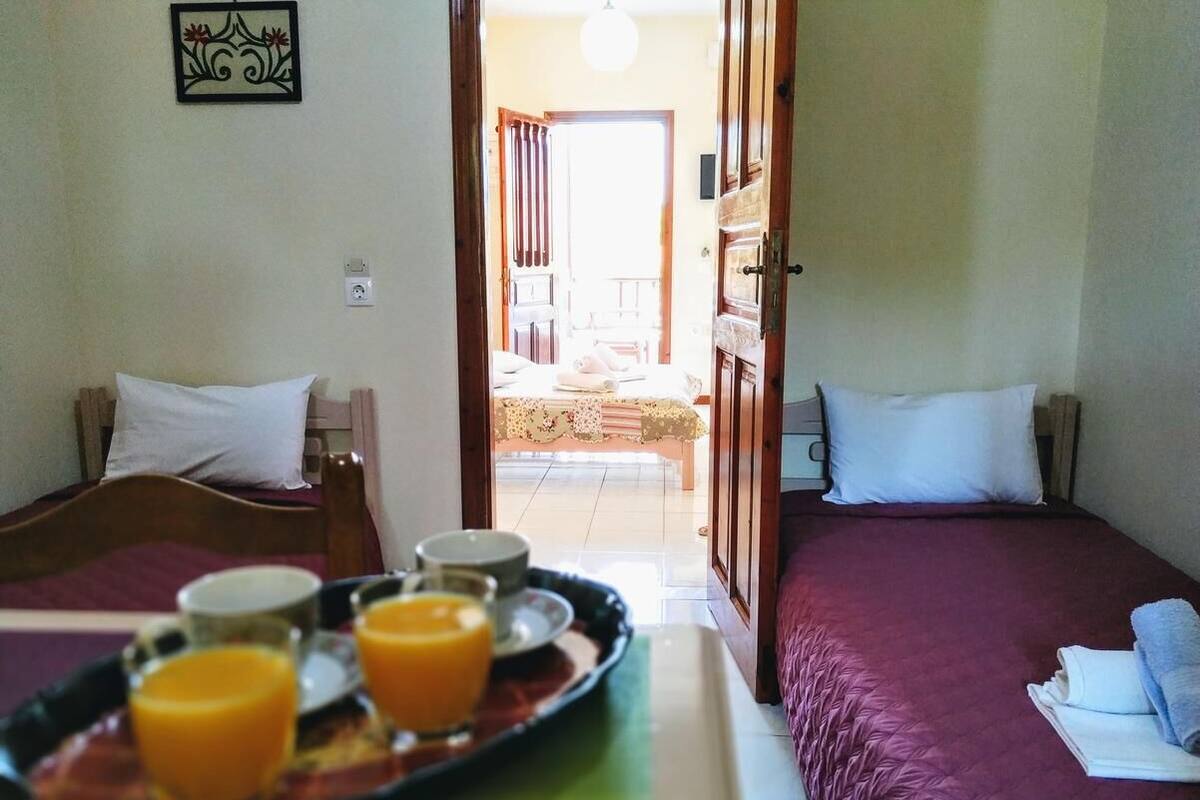 A hotel room with two beds, a breakfast tray with orange juice, and a view of the dining area.