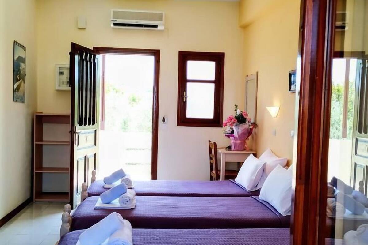 A room with two beds, a desk, and a window.