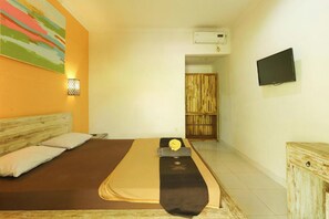 A hotel room with a bed, a wall-mounted TV, and an air conditioning unit. - The Legian Mas Beach Inn By Zuzu (Legian)