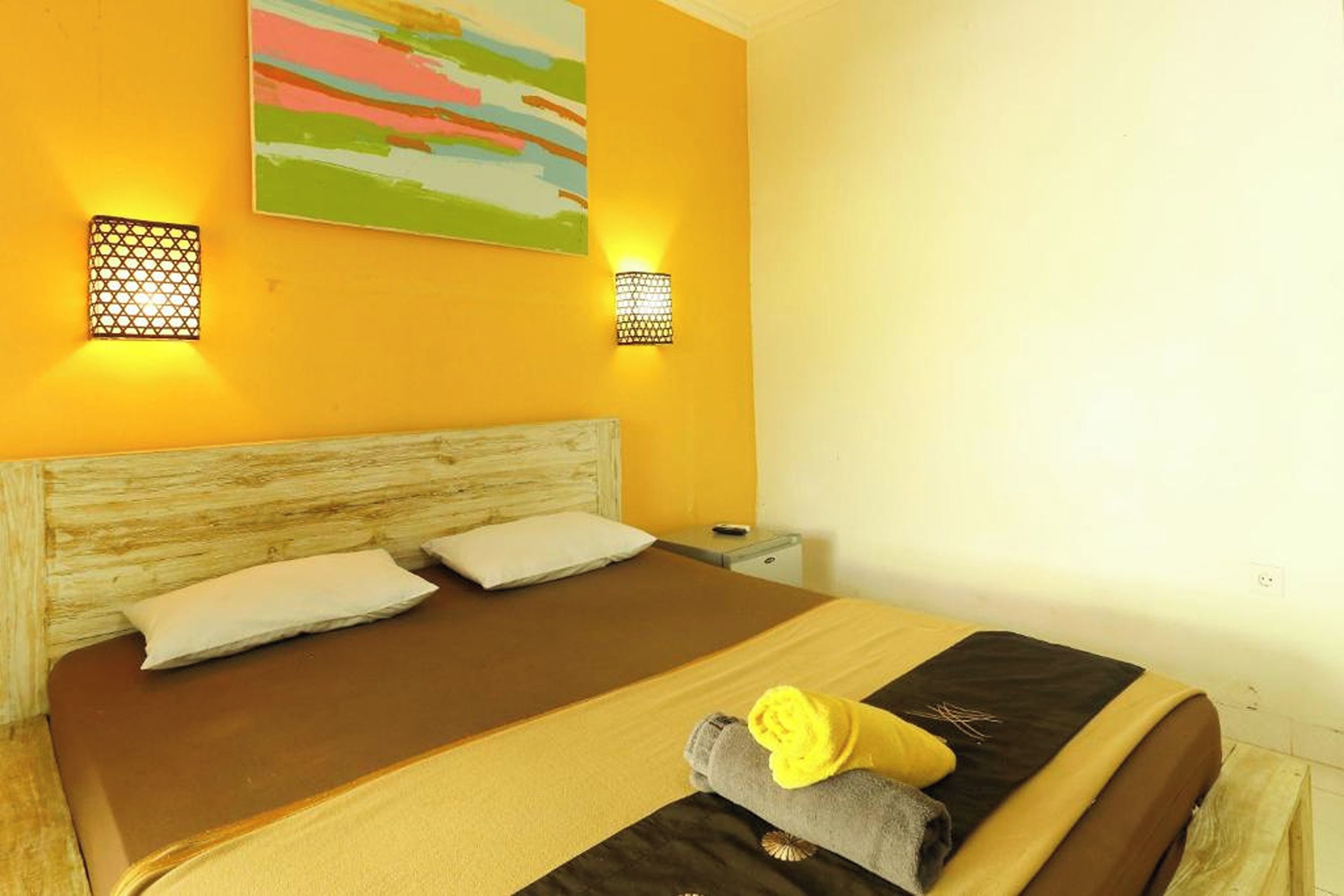 A bed with two pillows, a wooden headboard, and a nightstand with a lamp.