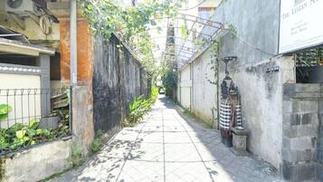 A narrow alleyway with a tiled walkway, a metal fence on one side, and a building with a sign that reads 'The Legion Mas' on the other.