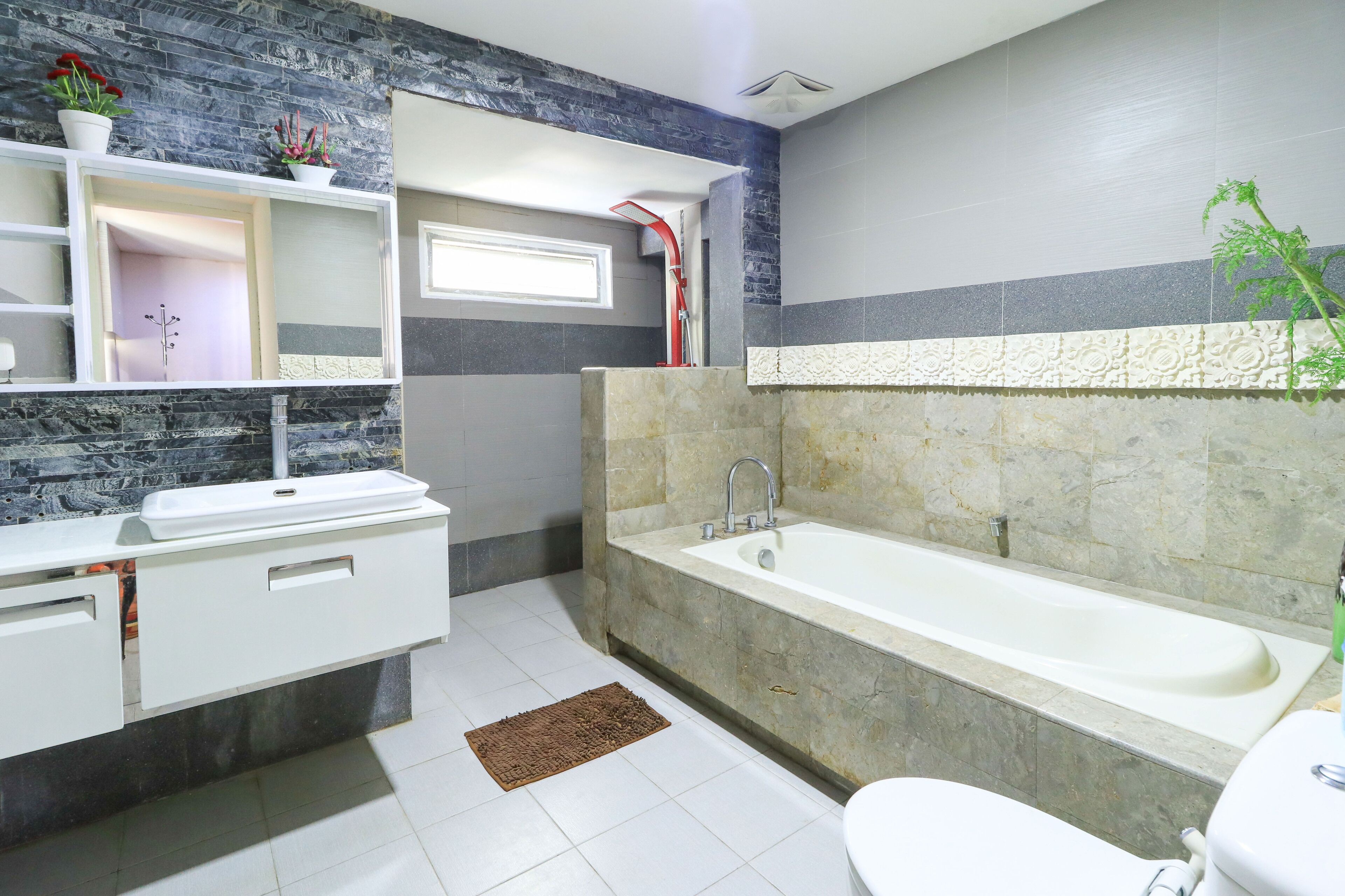 A modern bathroom with a white sink, a bathtub, and a toilet.