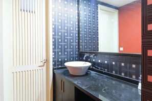 A bathroom with a white door, a black countertop, and a white sink. - Kubu Kalih Residence (Denpasar)