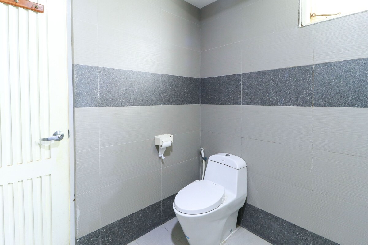 A small, clean bathroom with a toilet, a towel dispenser, and a door with a towel rack.