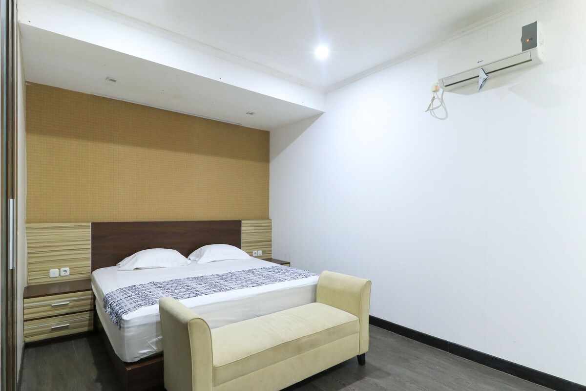 Una habitación de hotel con cama, mesita de noche y aire acondicionado instalado en la pared.
