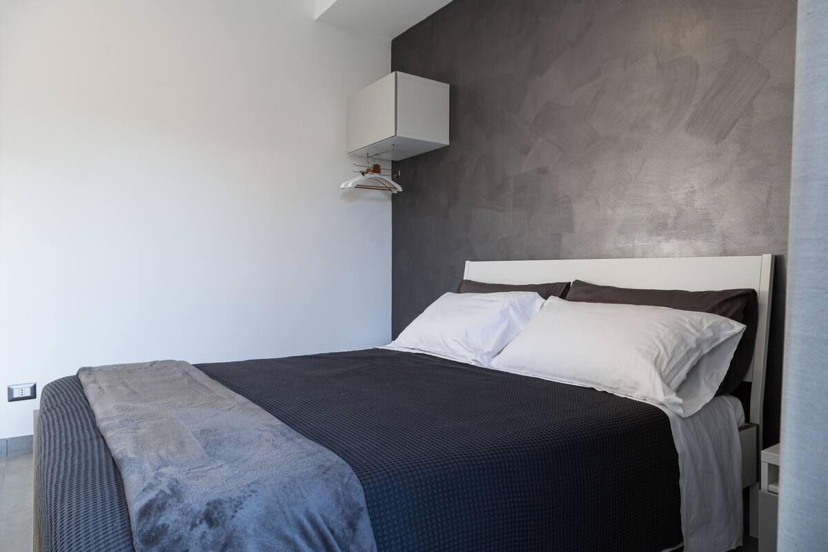 A modern bedroom with a bed, a wardrobe, and a wall-mounted cabinet.