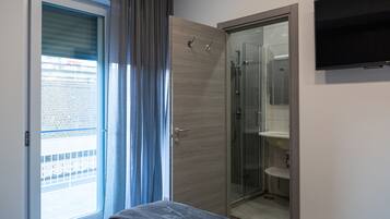 Ein modernes Schlafzimmer mit Bett, einer Schiebetür zum Balkon, einem begehbaren Kleiderschrank und einer Duschkabine.