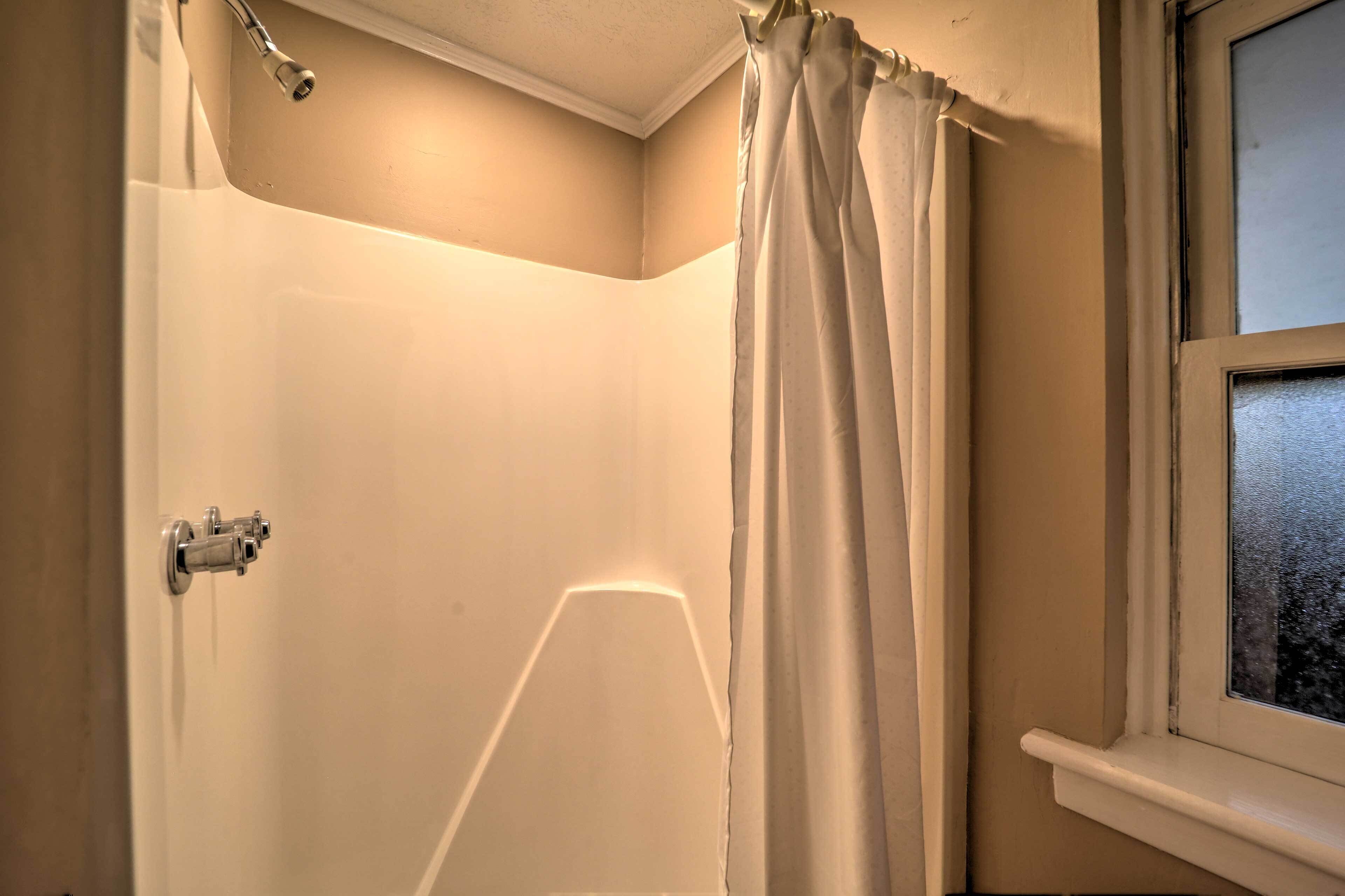 Une salle de bain avec une douche, une fenêtre et un rideau.