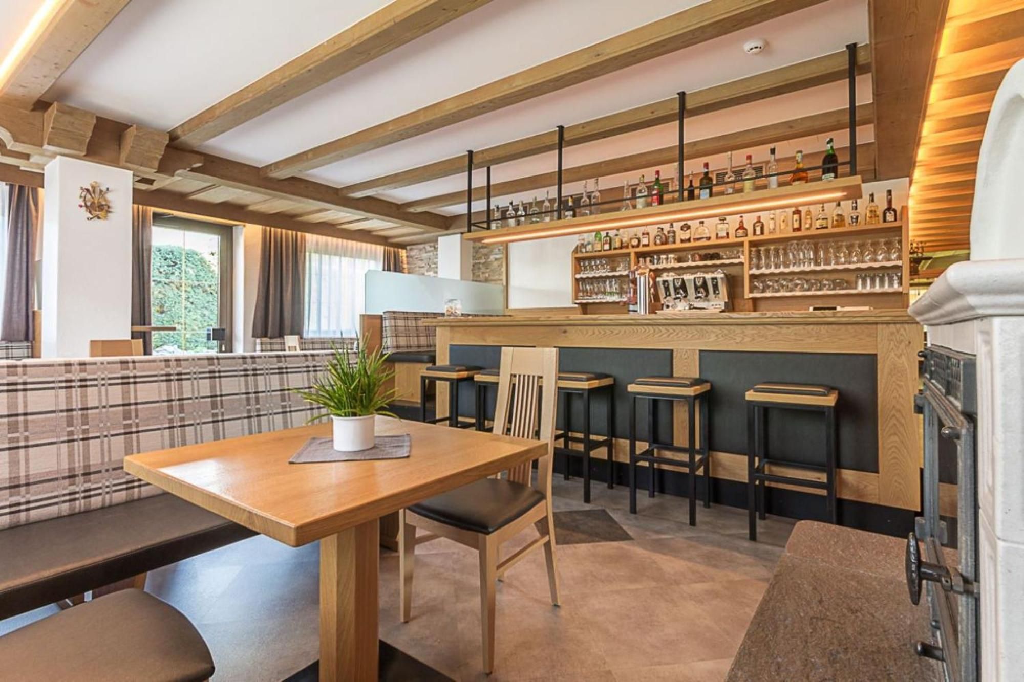 Un espace bar avec des poutres en bois, un comptoir et des tabourets.