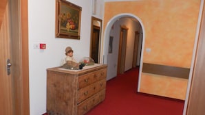 Un corridoio con una cassettiera in legno, un quadro e un tappeto rosso.