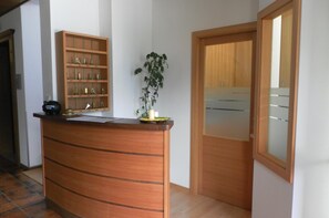 A reception desk with a wooden finish, a potted plant, and a glass display case with trophies.