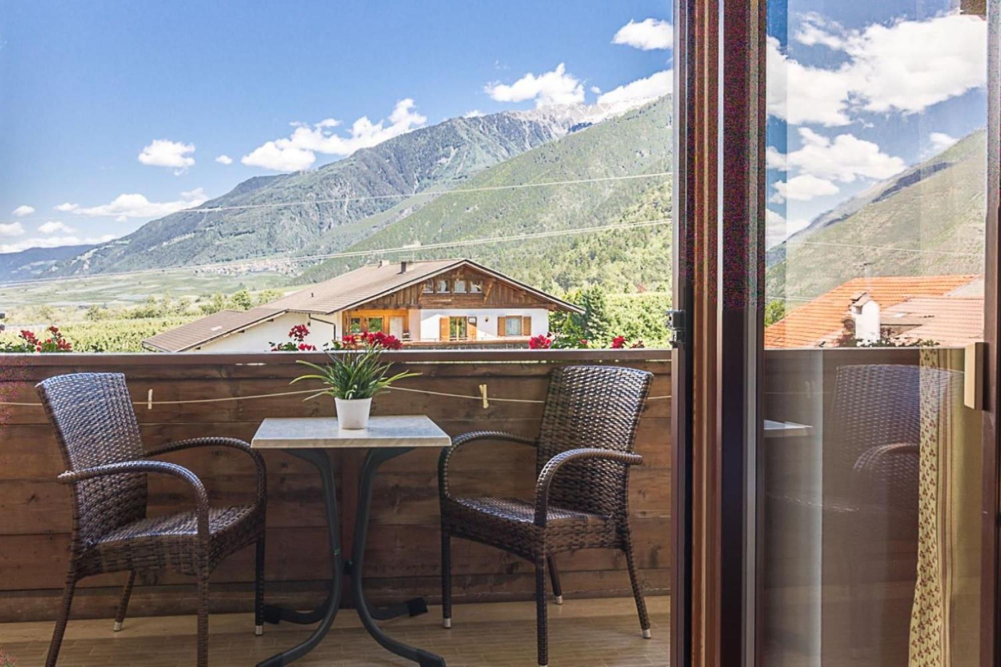 A balcony with wicker chairs, a table, and a potted plant.