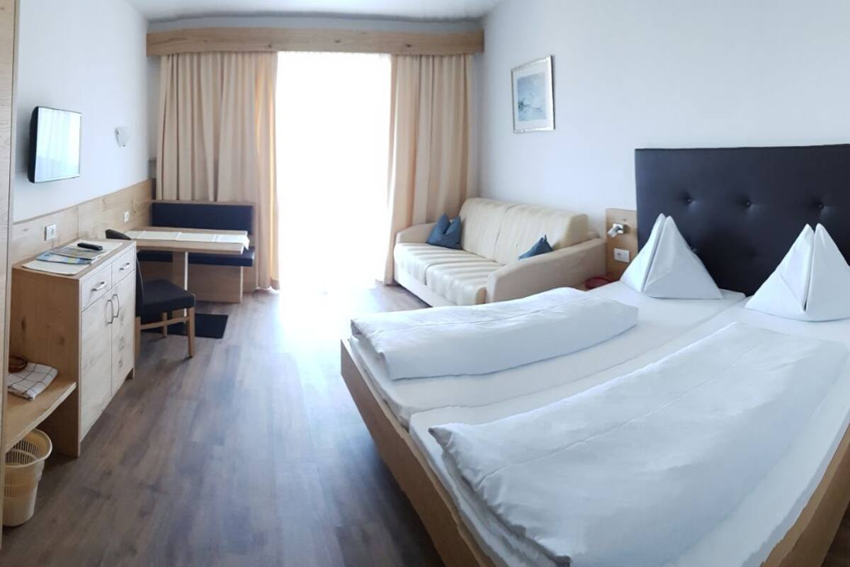 Una habitación de hotel con una cama, un escritorio, una silla, un sofá y un armario.