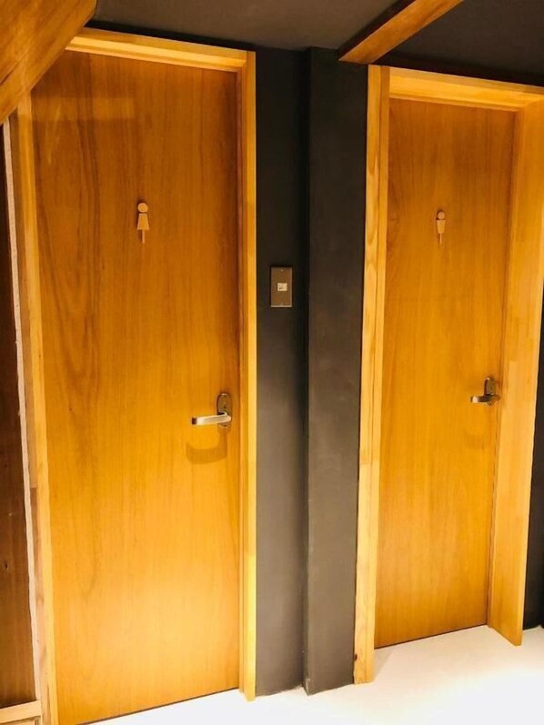 Two wooden doors with handles, a dark wall, and a light-colored floor.