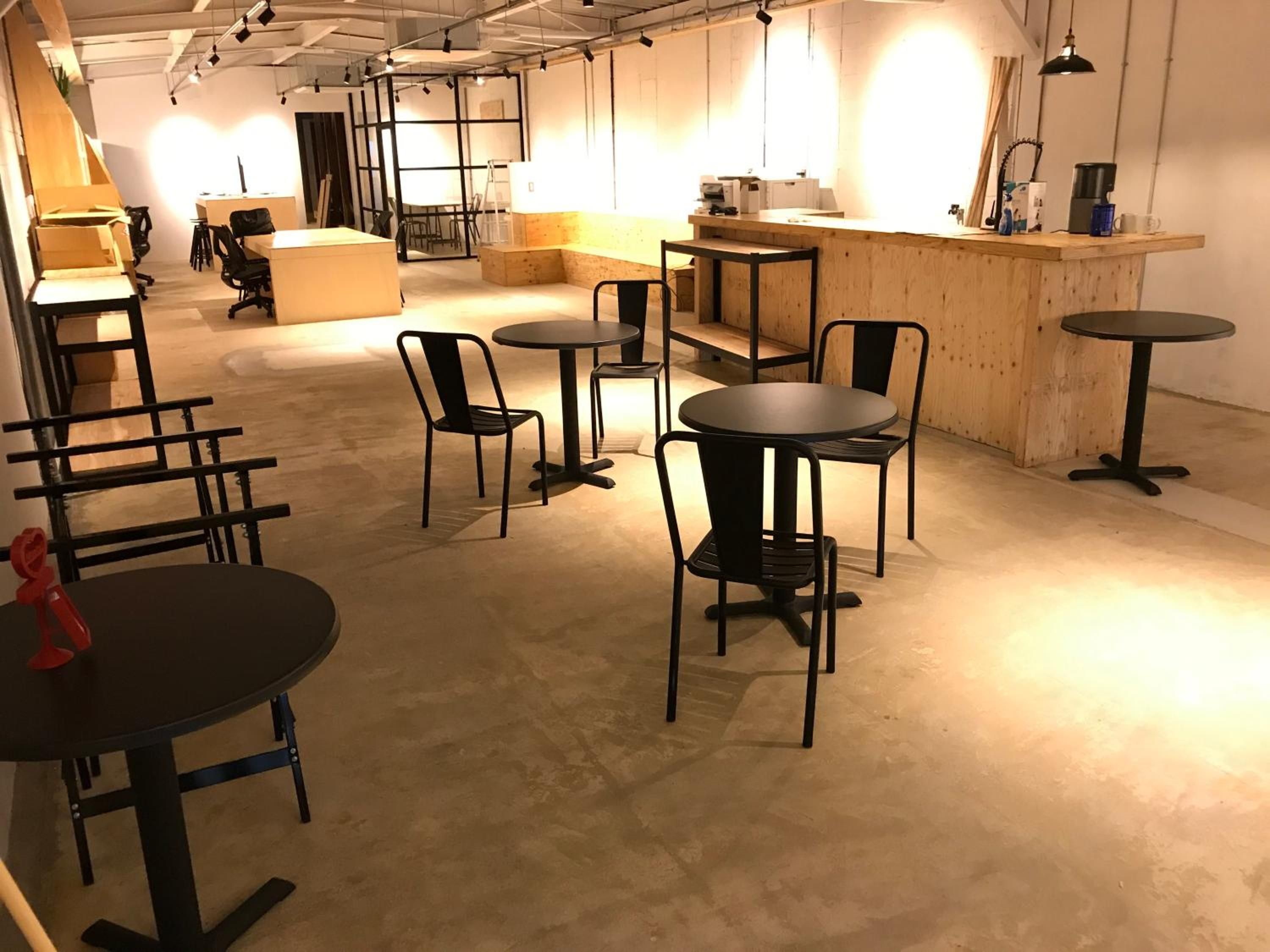 An indoor space with multiple tables and chairs, a wooden counter, and a visible door in the background.