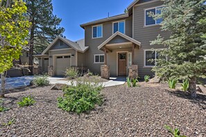 A two-story house with a stone entrance, a garage, and a landscaped front yard with gravel and small plants.