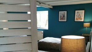 Une chambre à coucher avec un lit, une table de chevet avec une lampe et une fenêtre.