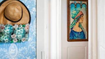 A hallway with a blue patterned wallpaper, a hat, and a framed artwork on the wall.