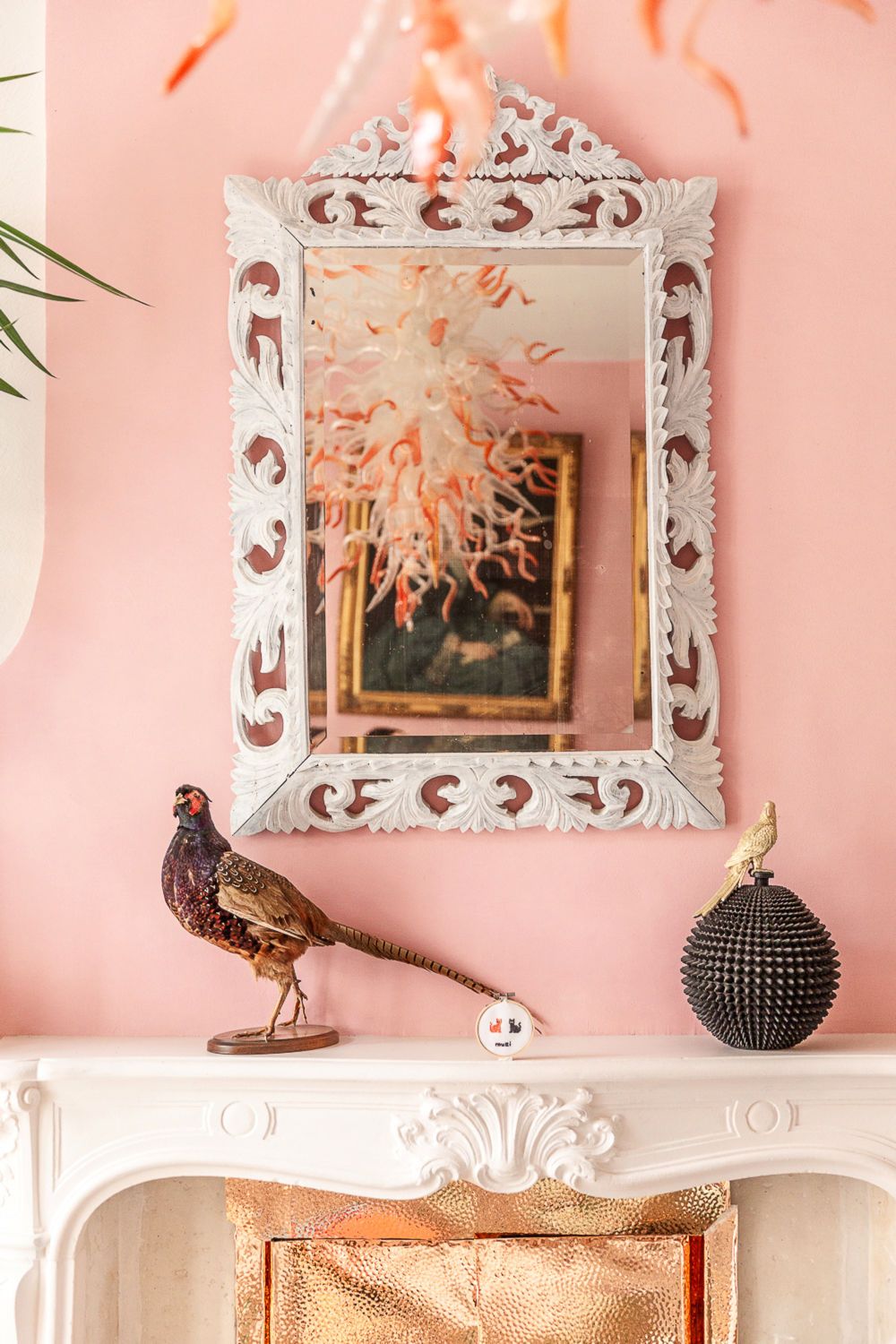 A white fireplace with a decorative mirror above it.