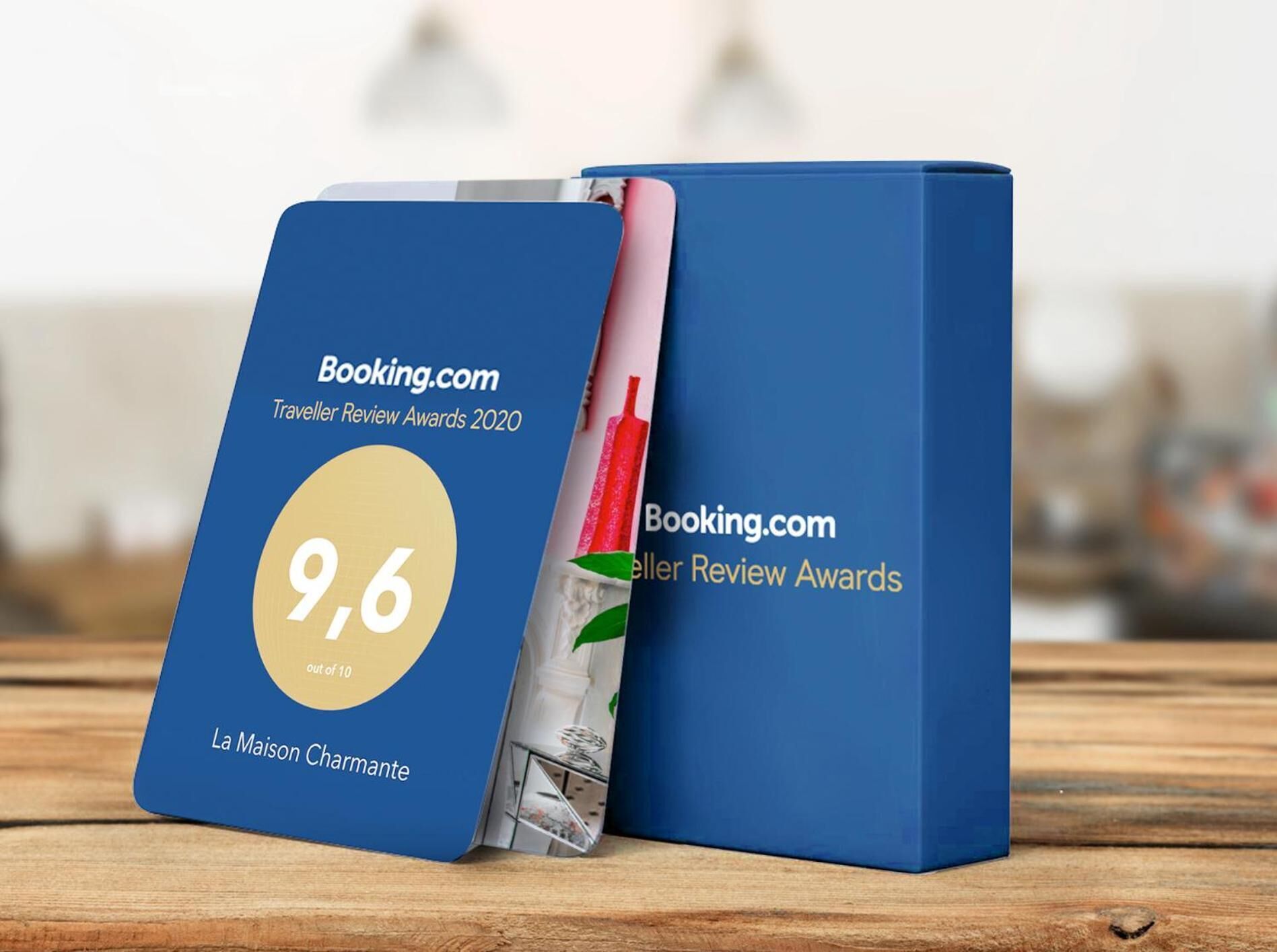A blue award plaque with a 9.6 rating for La Maison Charmante, displayed on a wooden surface.