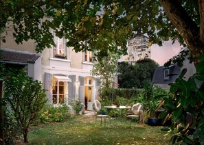 A traditional European-style house with a well-maintained garden, a patio with outdoor furniture, and a hanging birdcage. - La Maison Charmante (Chatellerault)