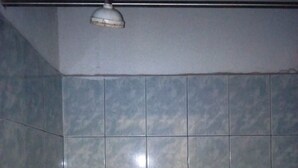 A bathroom with blue tiles, a toilet, and a shower. - Port View Guest House (Mombasa)