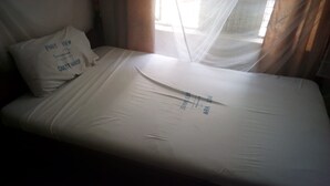 A single bed with a white mattress and a pillow with 'Port View Guest House' printed on it. - Port View Guest House (Mombasa)