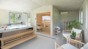 Uma casa de banho moderna com uma banheira grande, bancos de madeira e vista para uma paisagem montanhosa.
