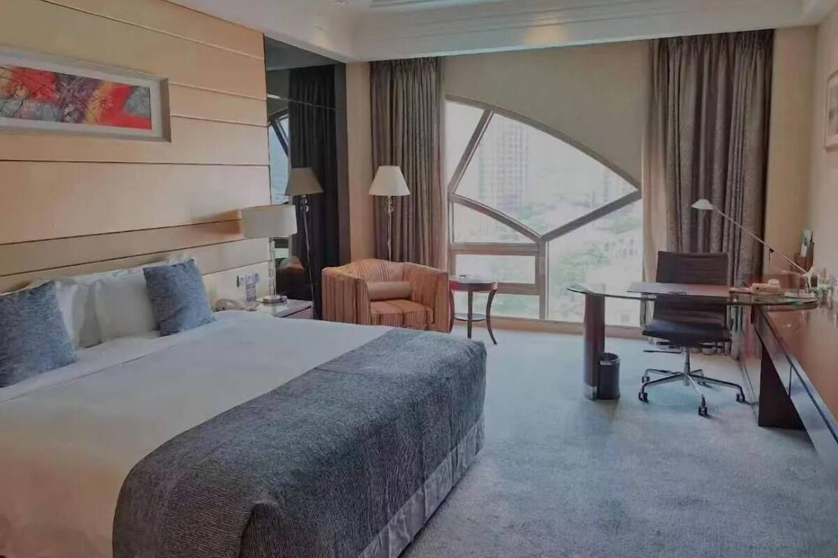 A hotel room with a large bed, a desk, a chair, and a window with a view.