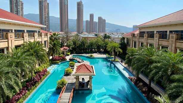 A resort with a swimming pool, palm trees, and high-rise buildings in the background. - Mingcheng Hotel Fuzhou (Fuzhou)