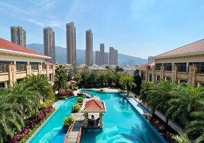 Um resort com piscina, palmeiras e edifícios altos ao fundo.