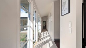 A long, narrow hallway with large windows on one side, allowing natural light to enter.