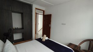 A hotel room with a bed, a wardrobe, a chair, and a mirror. - Rock Galana Holiday Apartments (Diani Beach)
