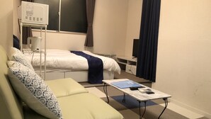 A compact hotel room with a bed, a small table, a sofa, and a TV. - Oval Tokyo Ikesan 201 (Tokyo)