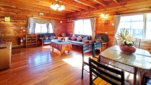 A wooden cabin interior with a sofa set, dining table, and chairs. - Nuowei Senlin Cottage (Ren'ai)
