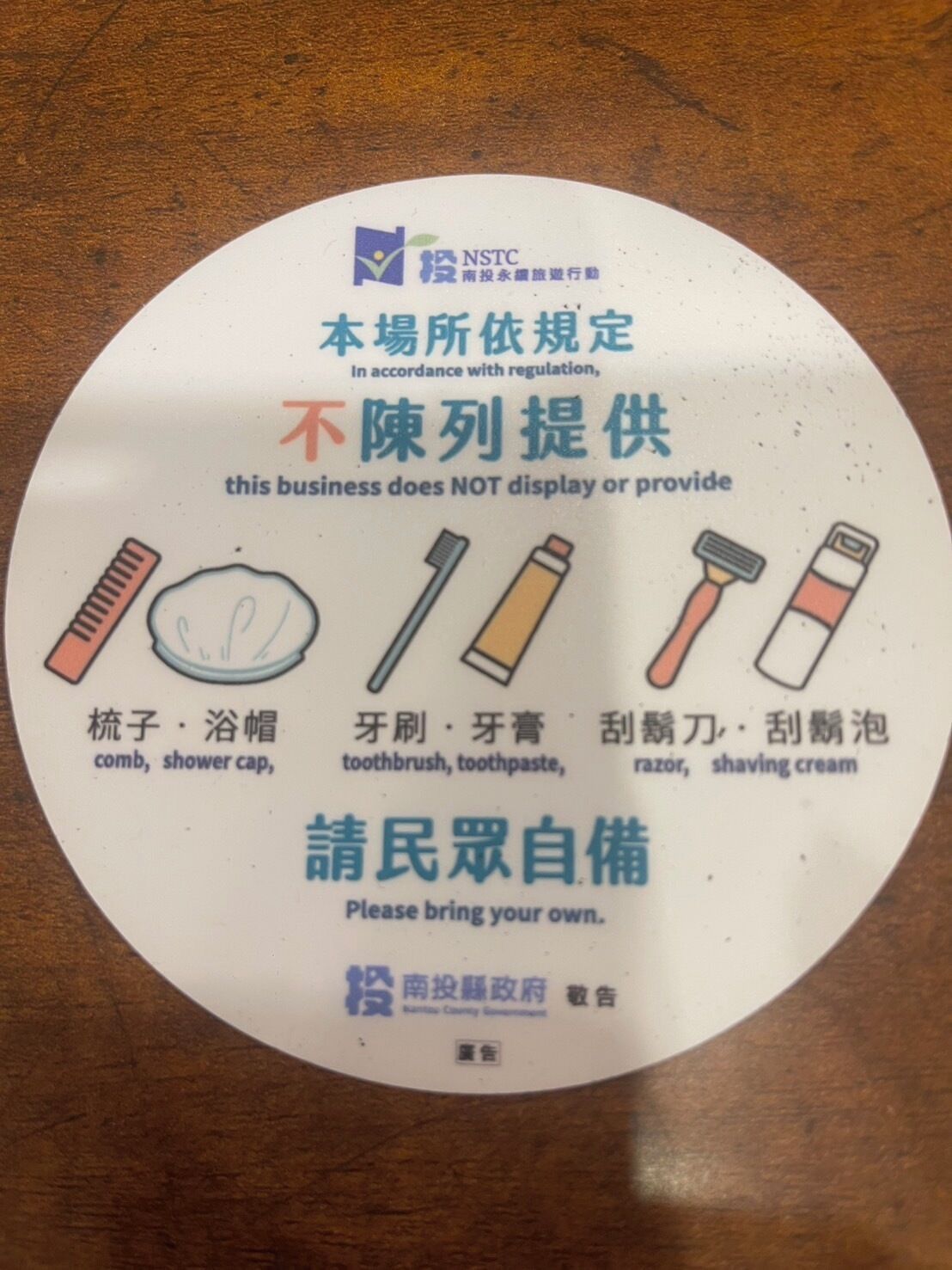 A circular sign with illustrations of personal care items and text in both English and Chinese, indicating that these items are not provided by the establishment.