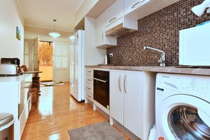A modern kitchen with a built-in washing machine, a microwave, and a sink with a faucet.