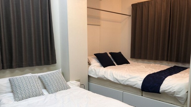 Ein Hotelzimmer mit zwei Betten, eines mit gemusterten Kissen und das andere mit schlichten Kissen.