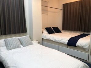 Quarto de hotel com duas camas, uma com almofadas estampadas e a outra com almofadas lisas.