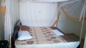 A bed with a canopy, a pillow, and a blanket. - Adonai Guest House (Mtwapa)