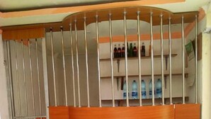 A room with a wooden partition, a blue plastic chair, and a shelf with bottles. - Adonai Guest House (Mtwapa)
